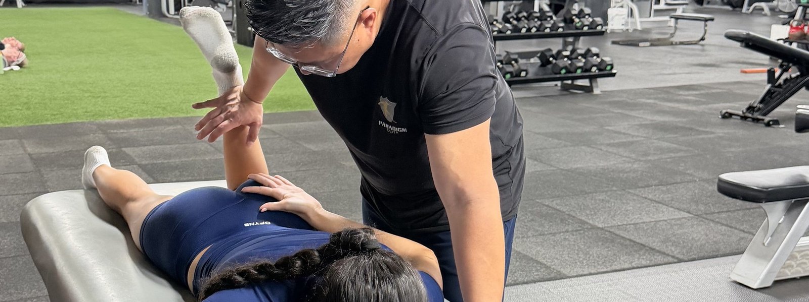 Dr. Stu performing a hands-on hip and leg assessment with a client on the treatment table